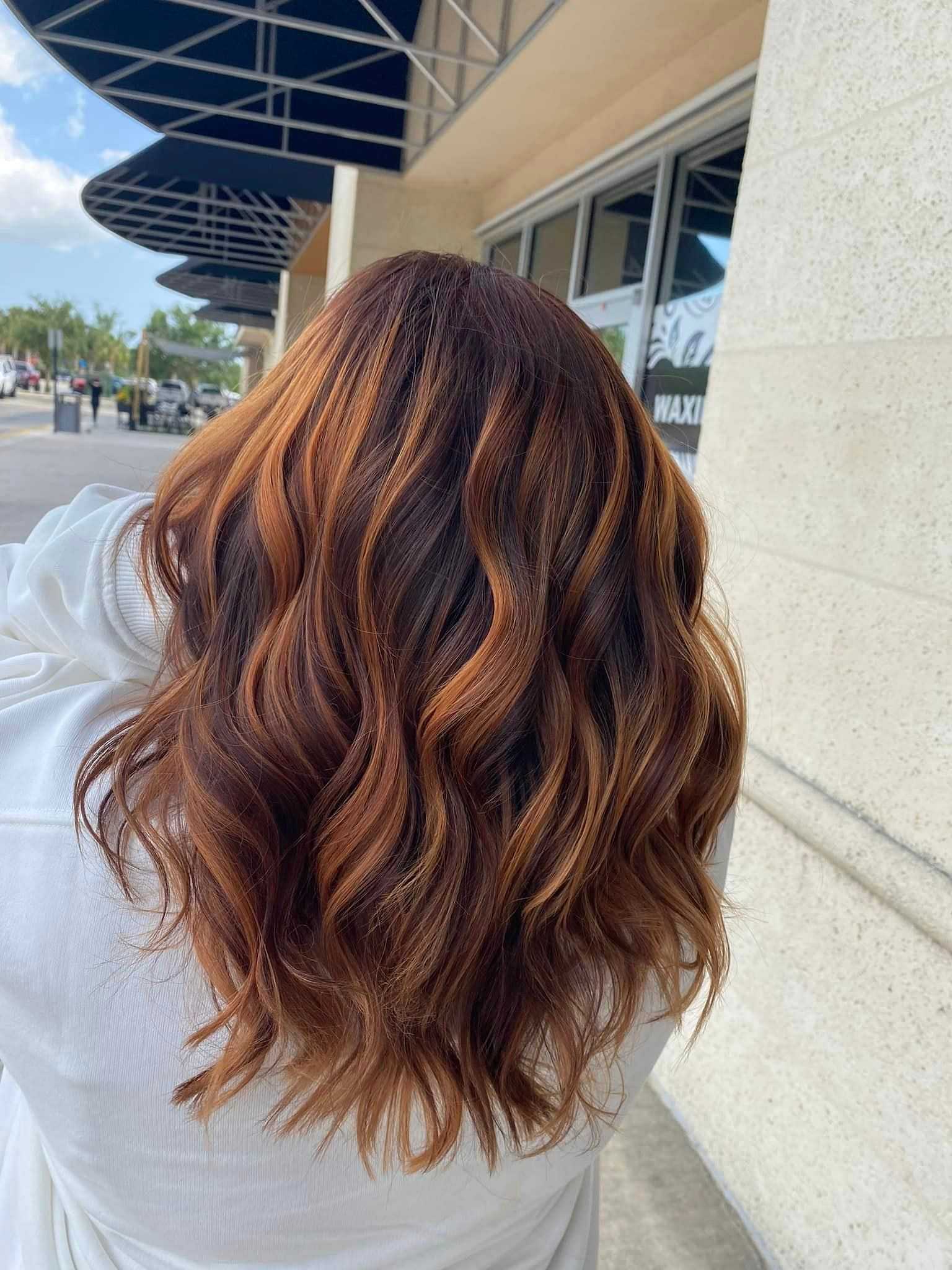 Woman with wavy auburn hair standing outside a storefront.