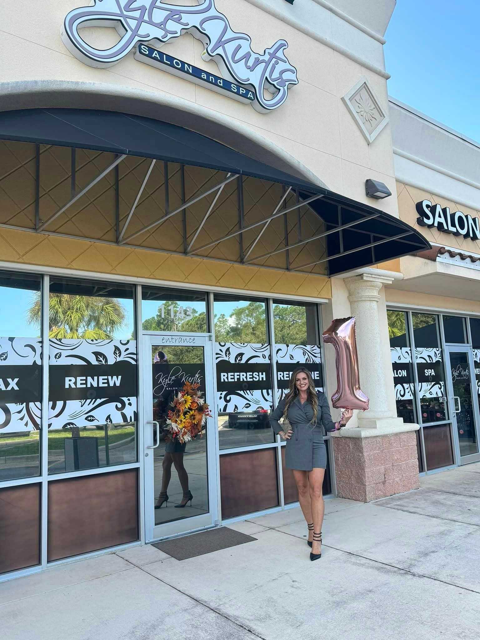 Woman in front of "Style Rush Salon and Spa," holding a balloon shaped like the number 1.