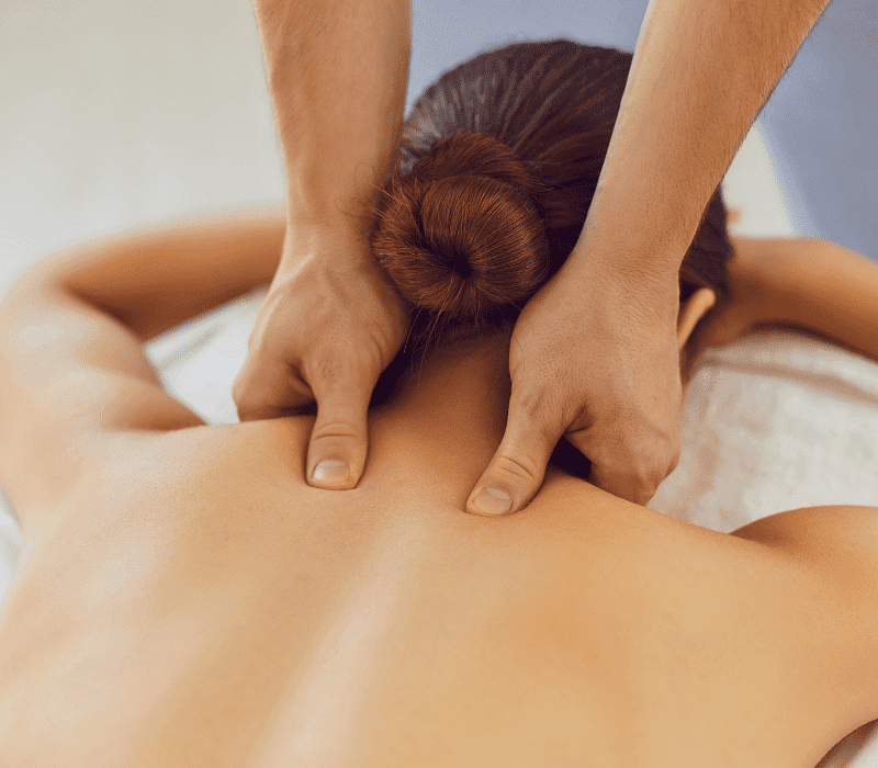 Person receiving a back massage, focusing on the shoulder blades and upper back.